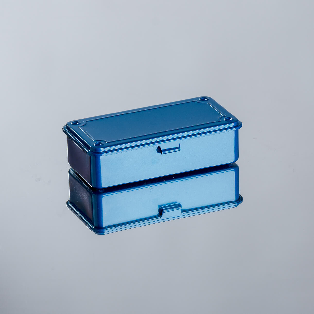 A small blue metal toolbox with a lid and a handle, on a plain background.