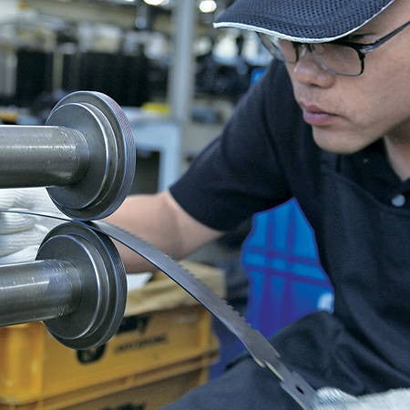A Silky worker feeding saw-blade steel through a machine at the factory in Ono, Japan